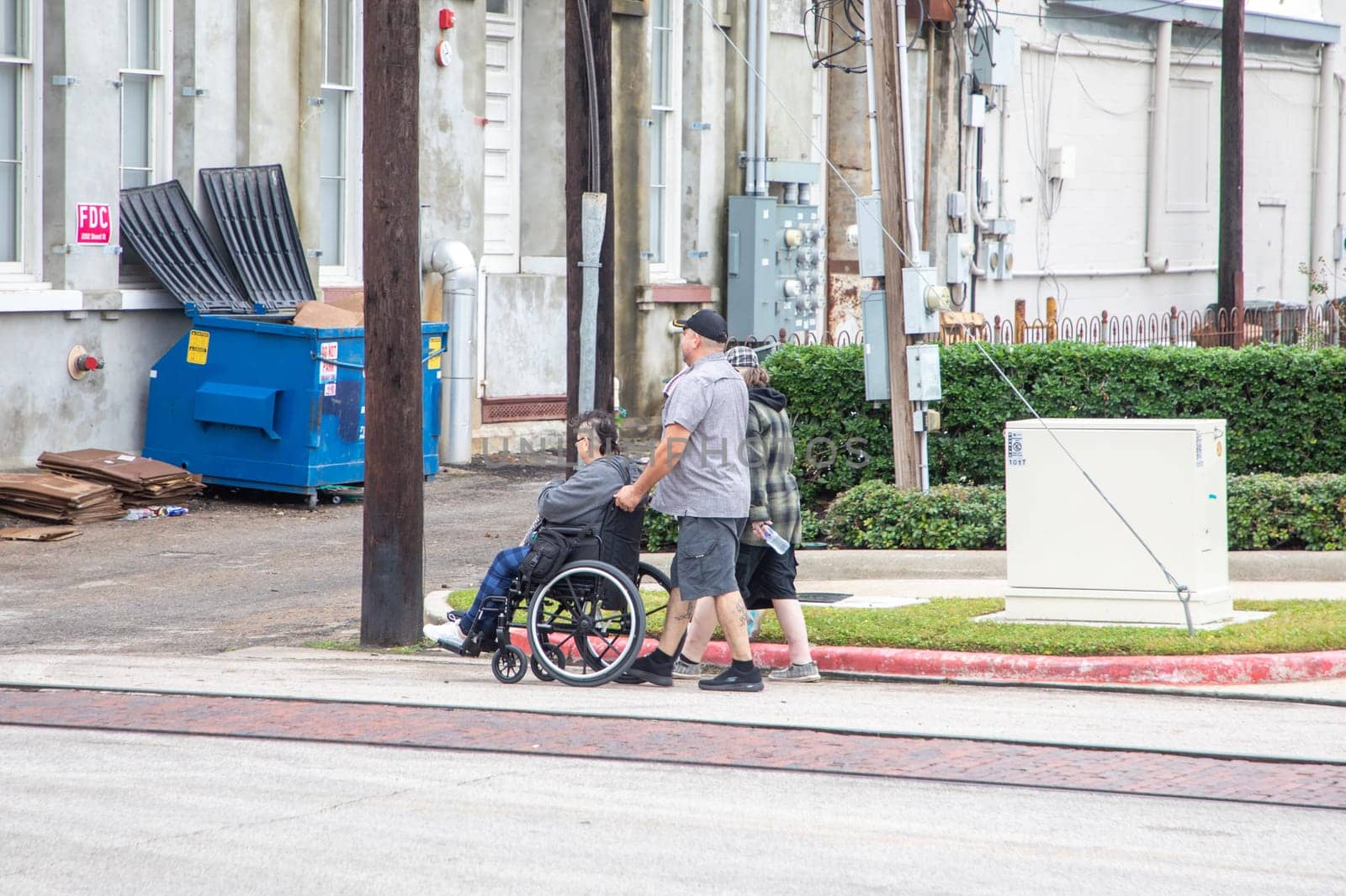 Galveston, USA - November 10, 2023: handicapped person at wheelchair with assistance by his family in the suburban area of Galveston, USA.