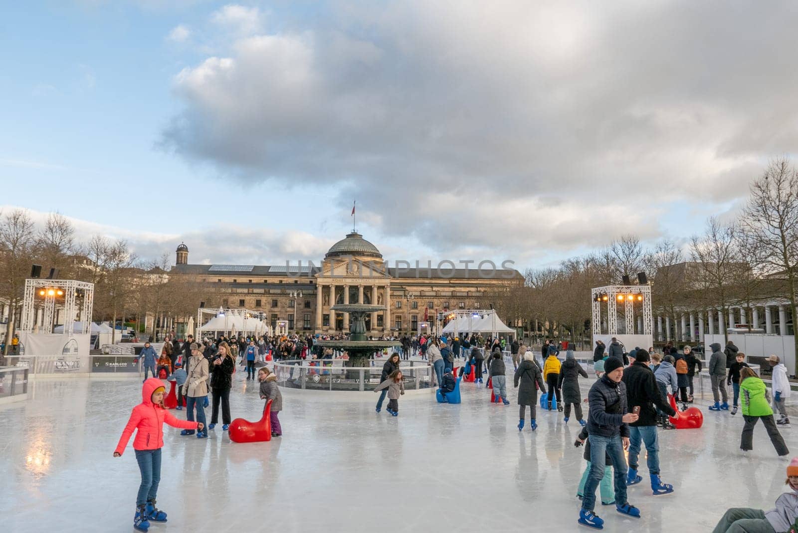 Wiesbaden, Germany - December 29, 2023: people enjoy the rink in front of the kurhaus in Wiesbaden, Hesse, germany.