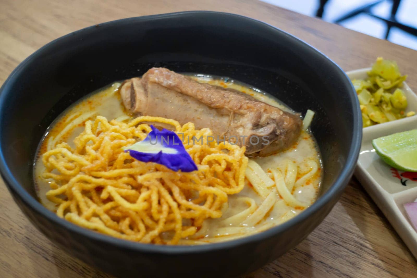Thai noodles Khao Soi, spicy curry with seasoning on table, stock photo