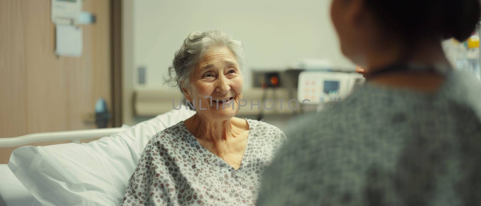 A senior woman's warm smile fills the hospital room as she chats with a caregiver, her spirit undiminished by her surroundings