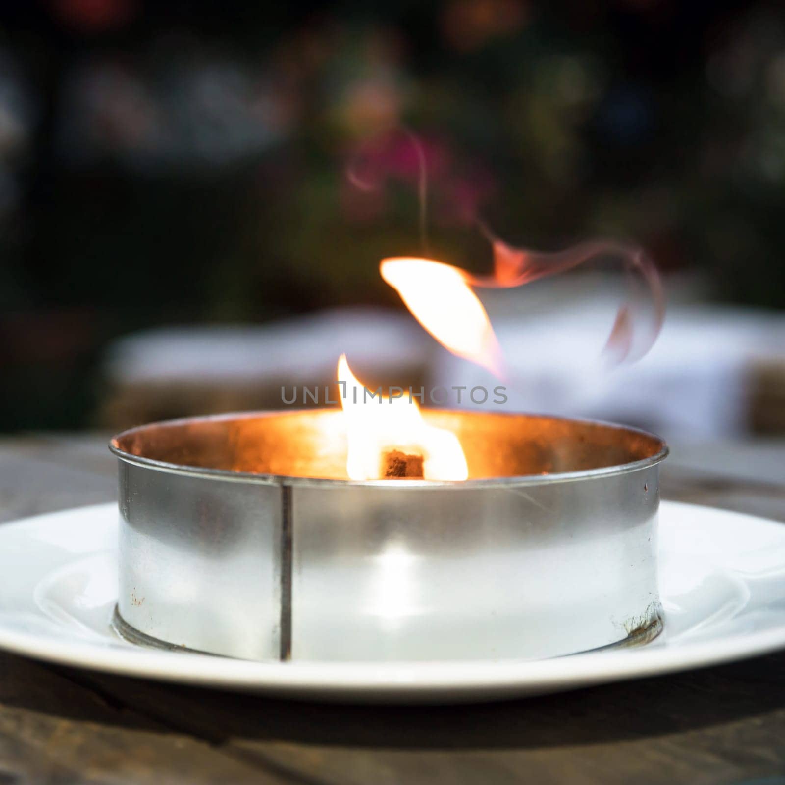 Decorative metal candle on blurred background. Burning decorative candle. Close-Up.