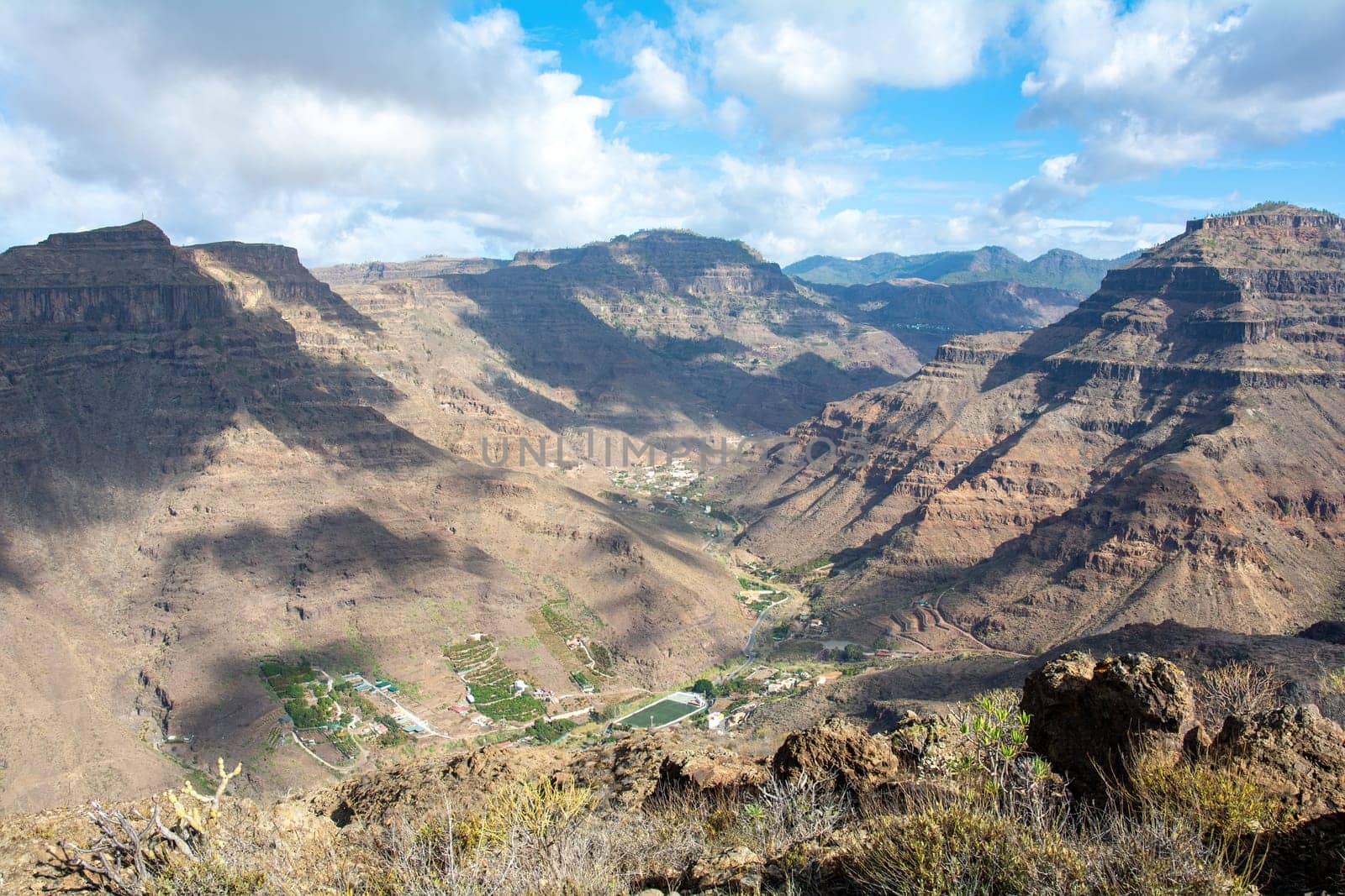 Mountains with a small village in the valley on the Canary Island of Gran Canaria in Spain, with blue sky and clouds