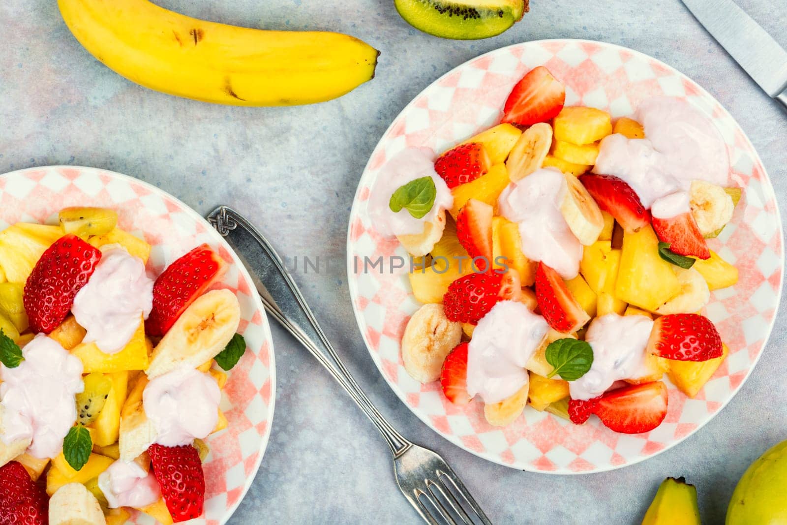 Summer fruit salad of pineapple, strawberries, kiwi and yogurt on a plate.