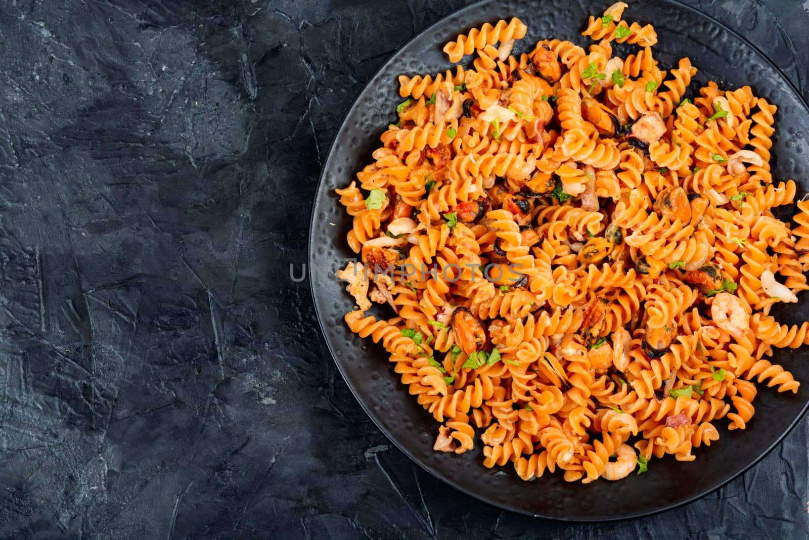 Mediterranean pasta or macaroni with seafood, pasta with mussels and shrimp on a plate.