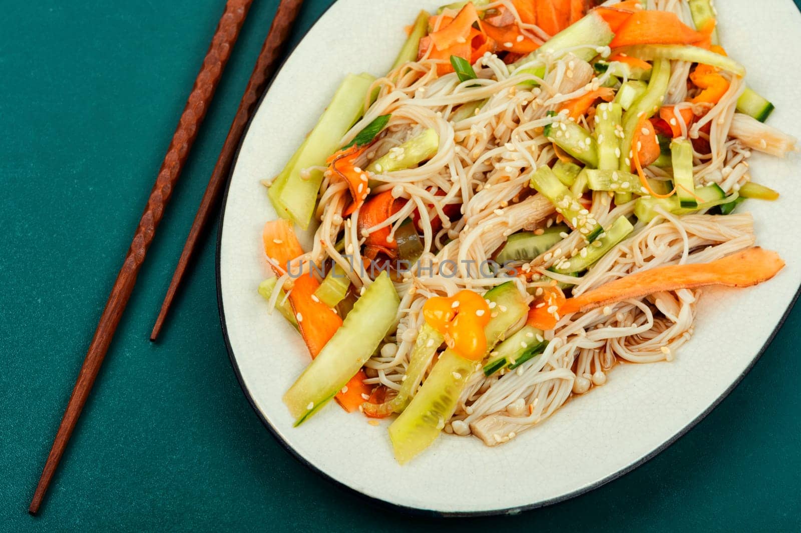 Vegan salad with enoki mushrooms, carrots, cucumber, fried sesame seeds. Healthy diet concept.