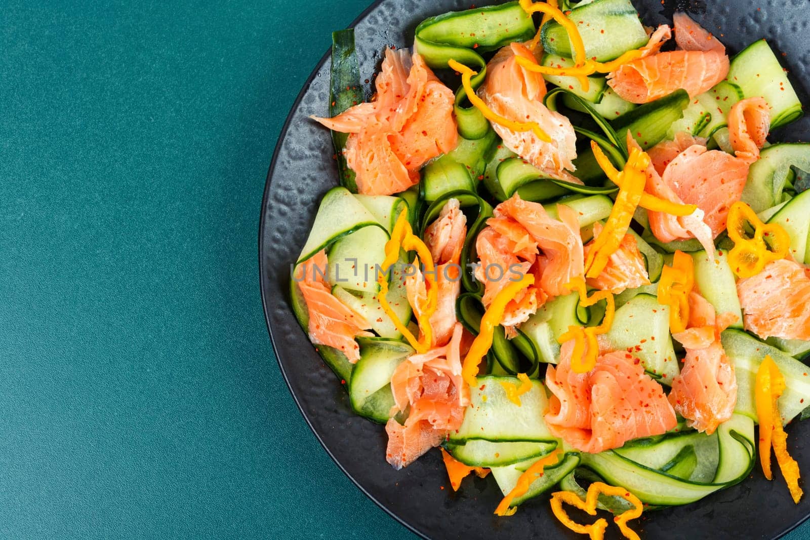 Fresh spring salad with smoked salmon, cucumber on a concrete kitchen table. Asian cuisine.