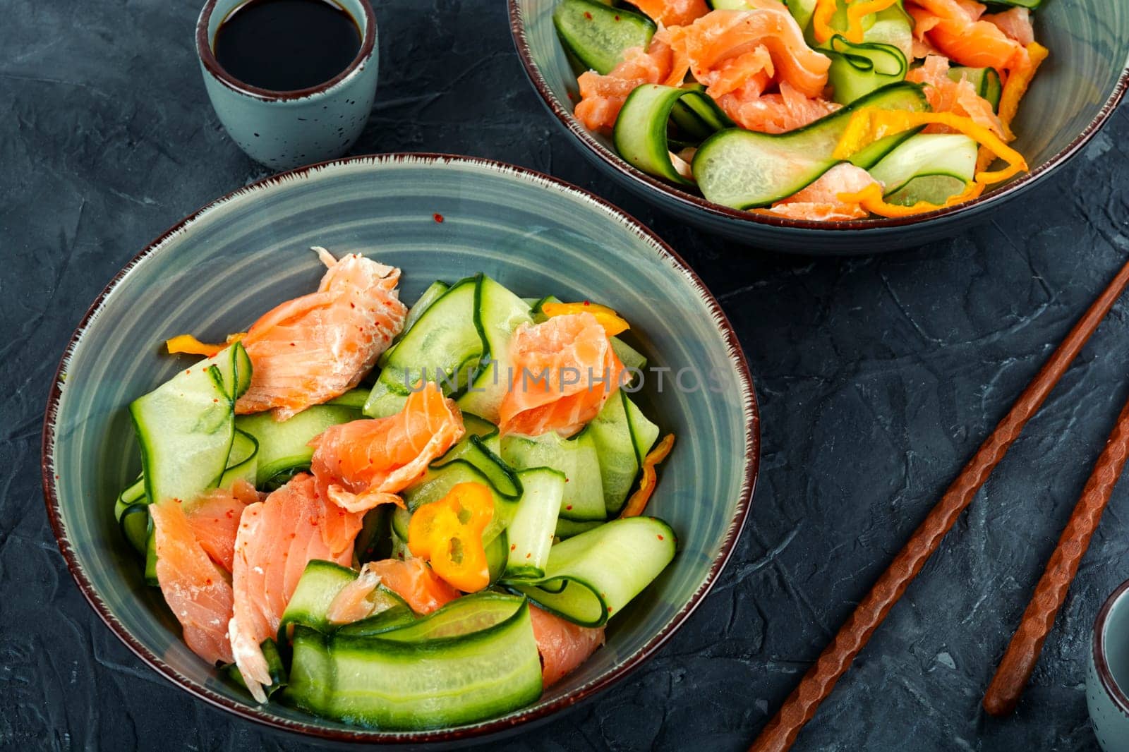 Fresh spring salad with smoked salmon, cucumber on a concrete kitchen table. Asian cuisine.
