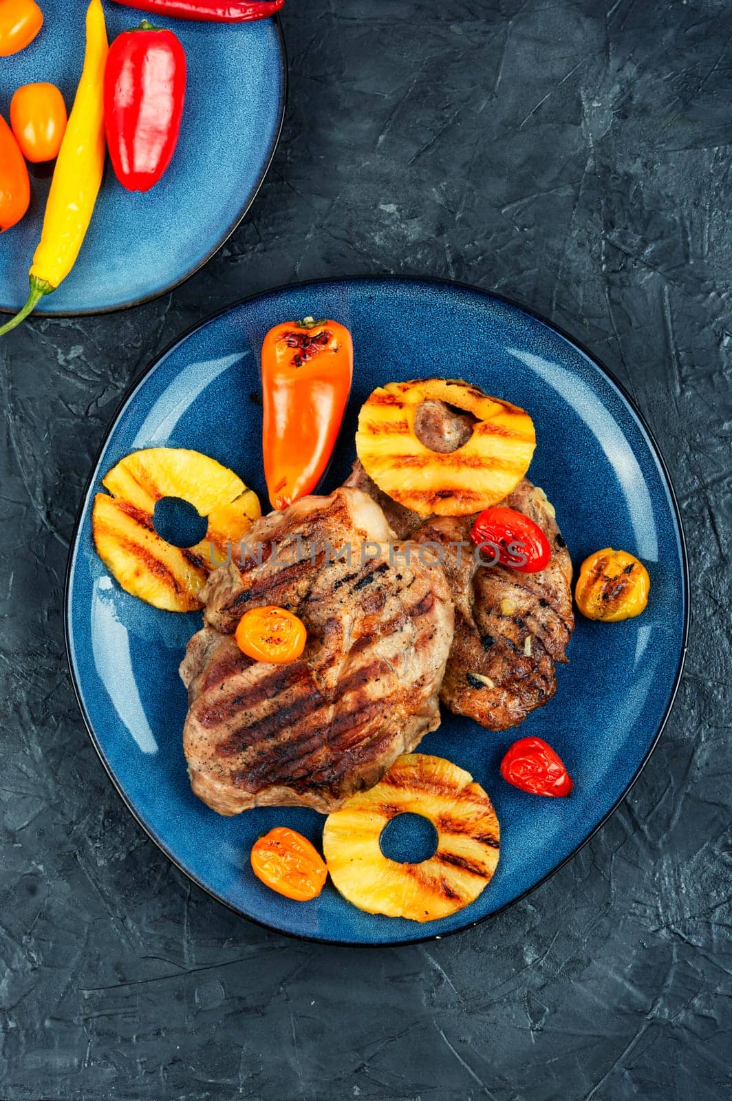 Tasty grilled meat,roasted with pineapple on stone background. Grilled steak and ananas. Top view.