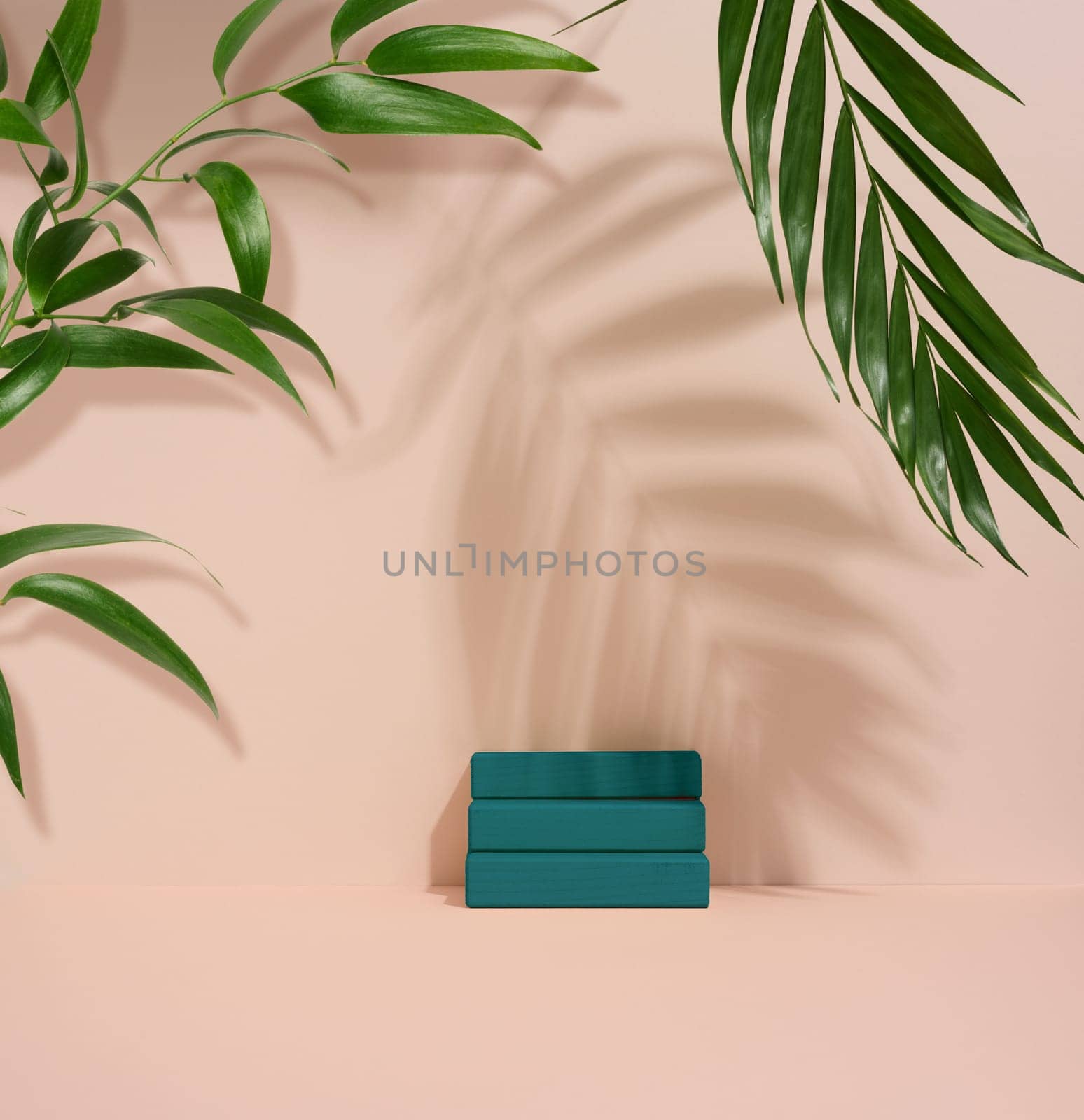 Wooden steps and shadow from a palm leaf on a beige background. Stage for demonstration and advertising of products, cosmetics, goods