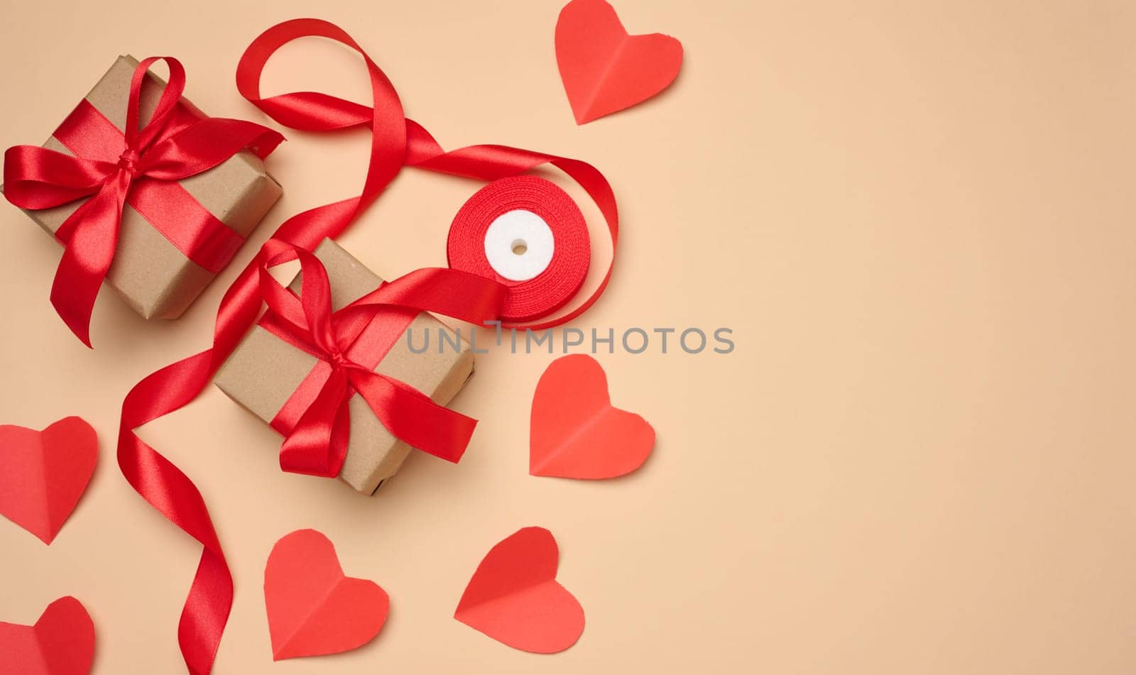 Gift box with red satin ribbon and bow on a beige background. Holiday background, copy space
