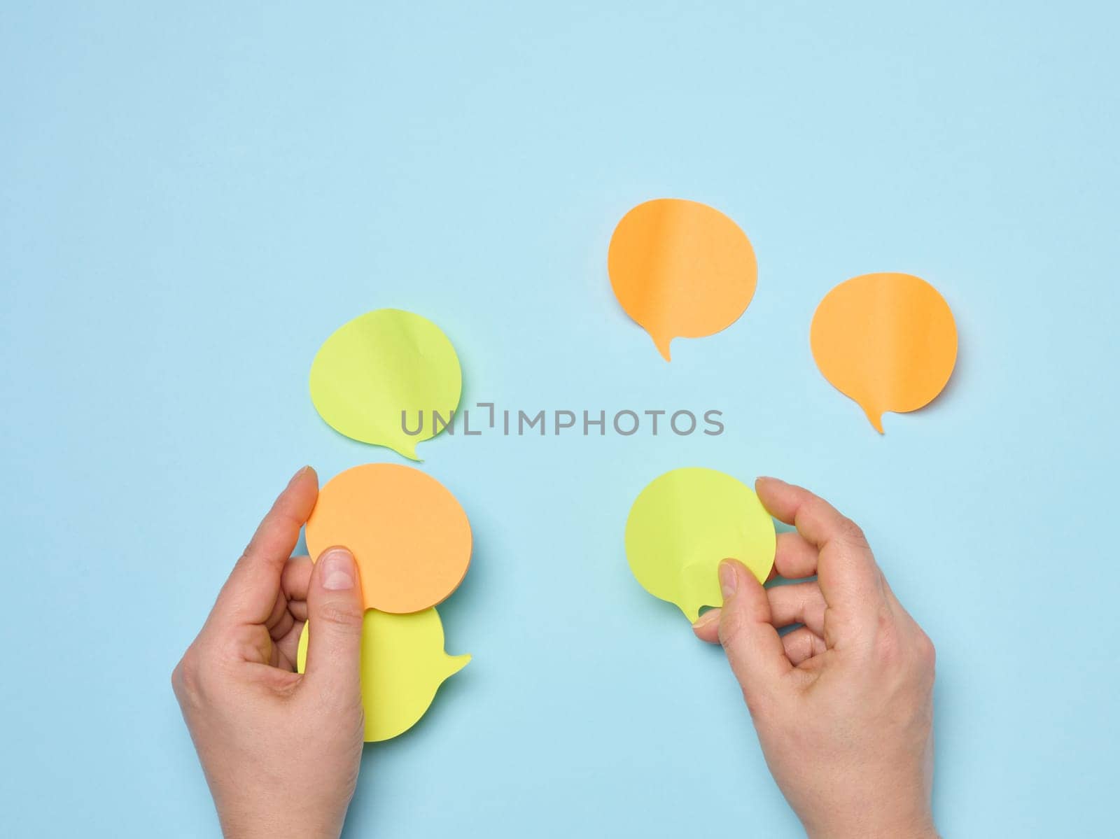 Paper stickers in the shape of a cloud in female hands on a blue background