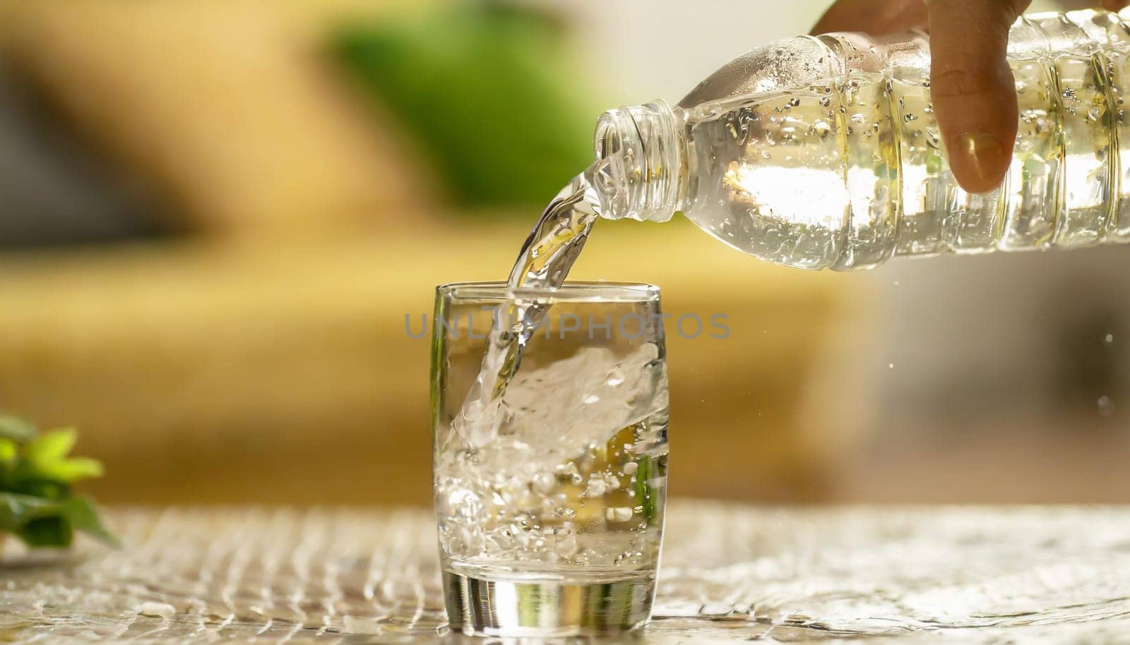 Close up the pouring purified fresh drink water from the bottle on table in living room