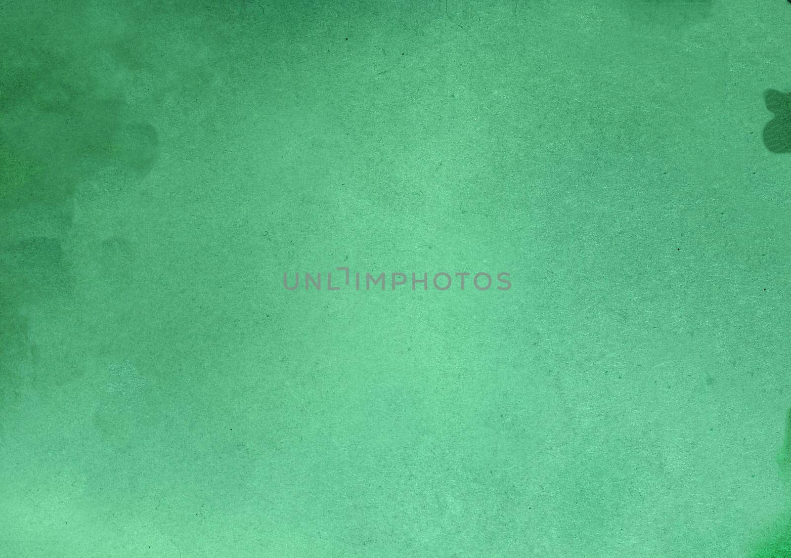 Background texture of a rough surface with villi, spots and particles on a green background close-up view from above