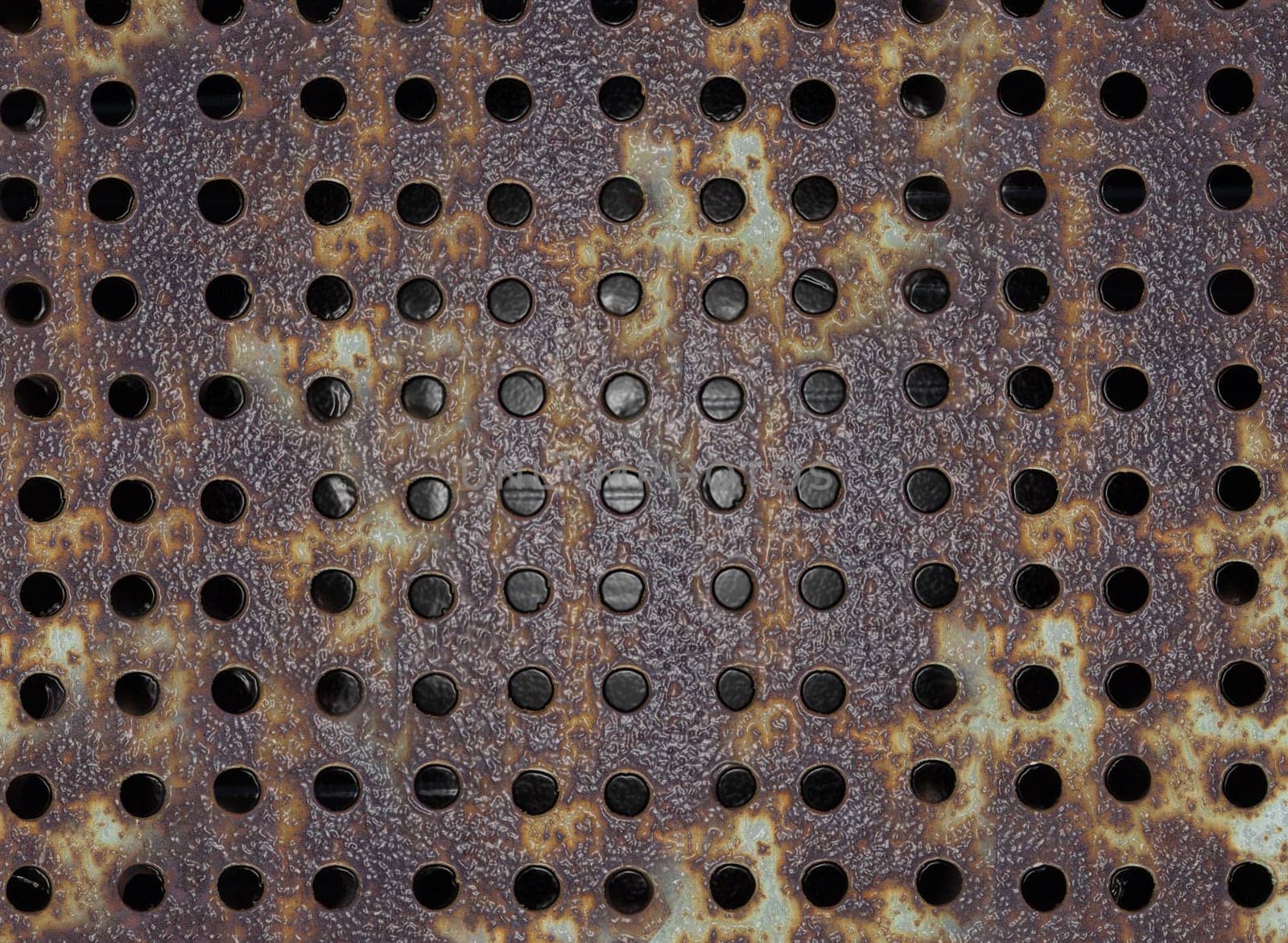 Background texture of a rusty metal plate with round holes on the surface close-up