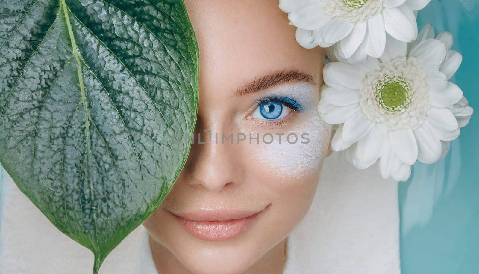 Portrait of beautiful woman with healthy glow perfect smooth skin holds tropical leaf, look into the hole of green paper. Young girl enjoys cream facial mask. Fashion, beauty, skincare concept.