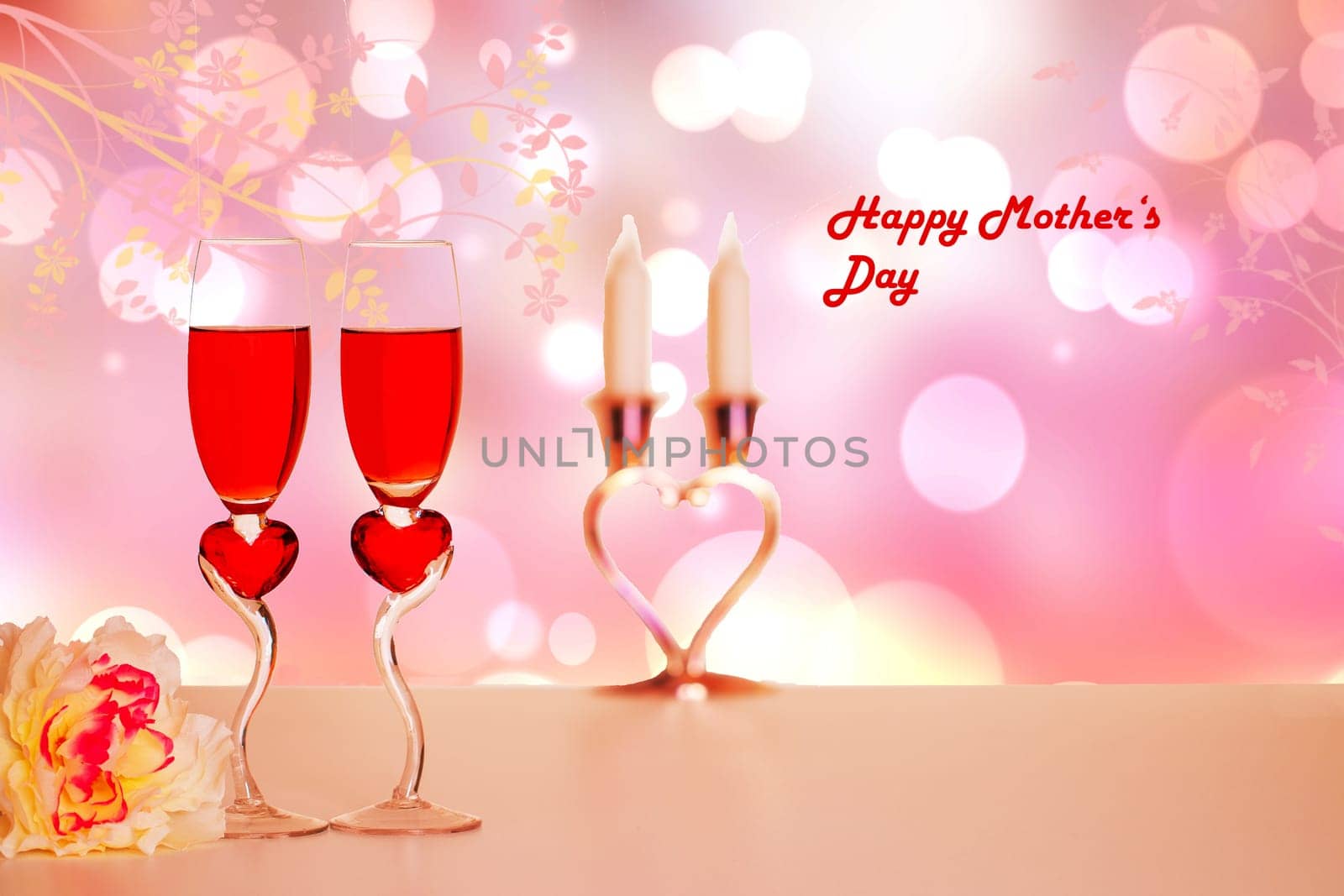 Happy Mothers Day card. Two glasses of champagner, a bouquet flowers on table over abstract heart background with Happy Mothers inscription. Copy space.