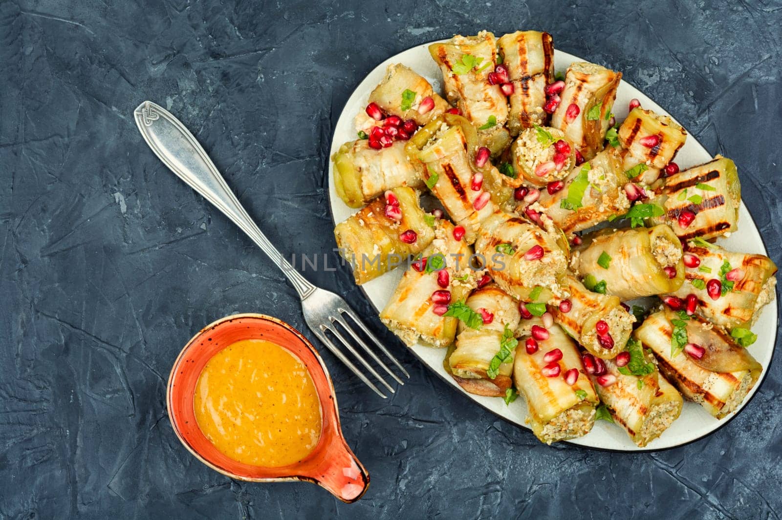 Fried eggplant rolls with walnut, garlic filling and decorated with pomegranate. Badrijani