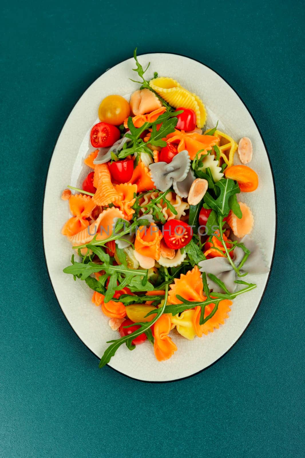 Salad with fresh tomatoes, greens and pasta on a plate.