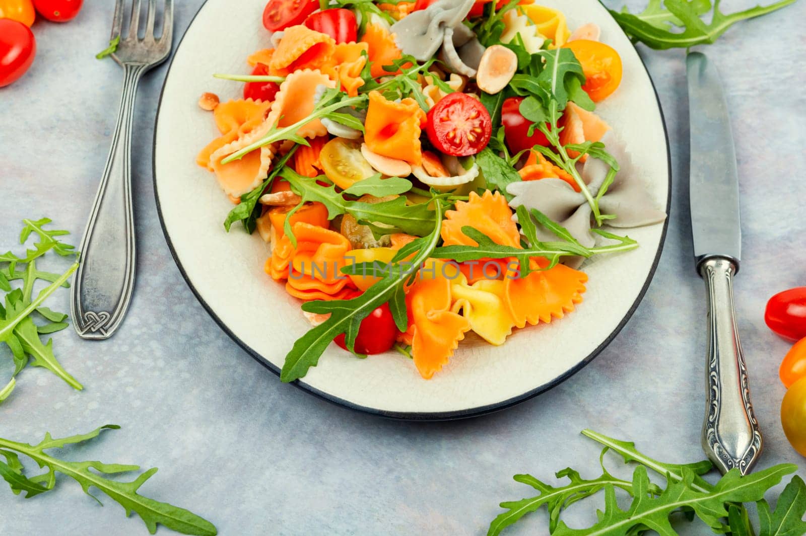 Salad with fresh tomatoes, greens and pasta on a plate.
