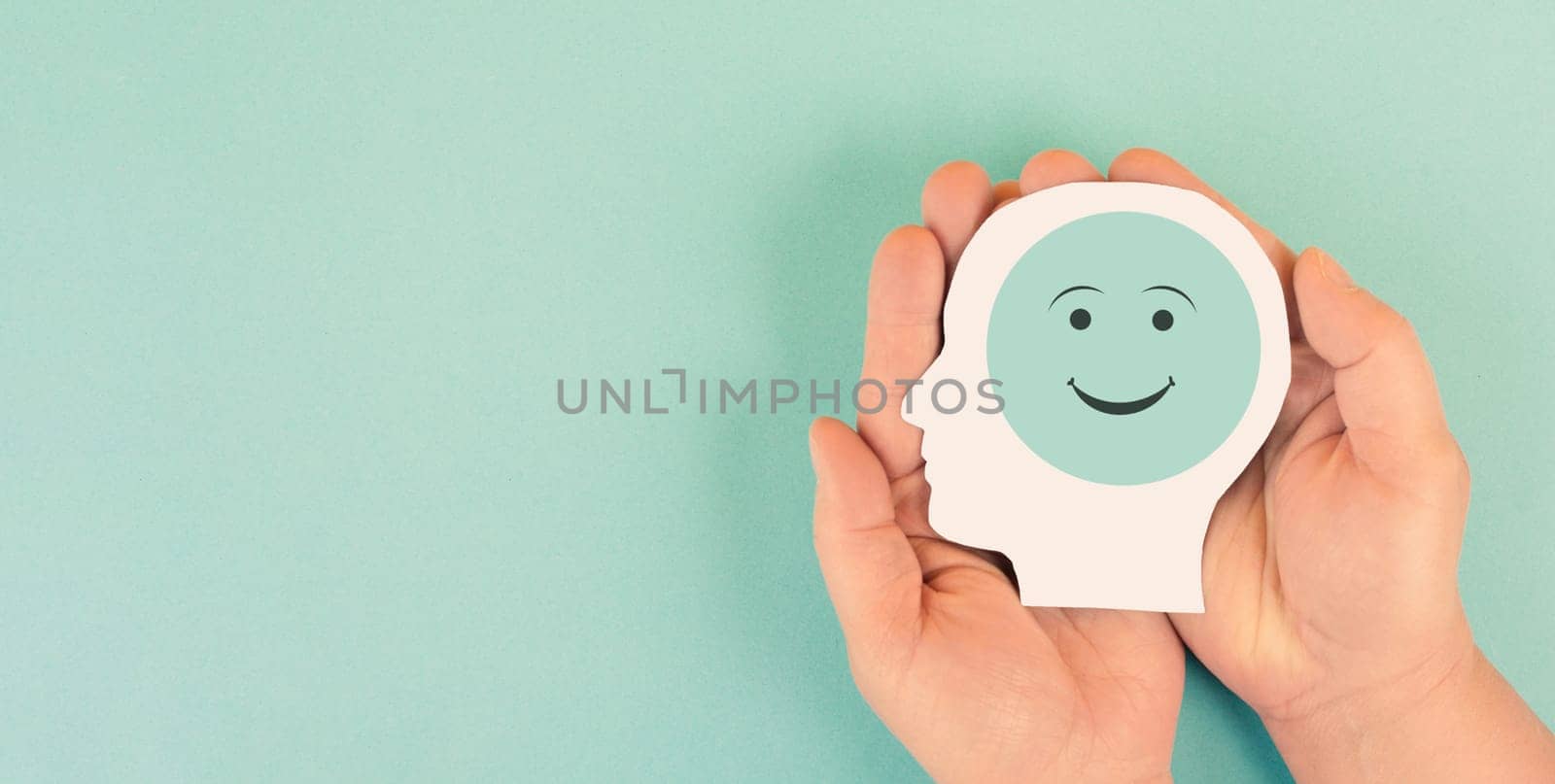Holding a head with a happy smiling face in the hands, mental health concept, positive thinking, support and evaluation
