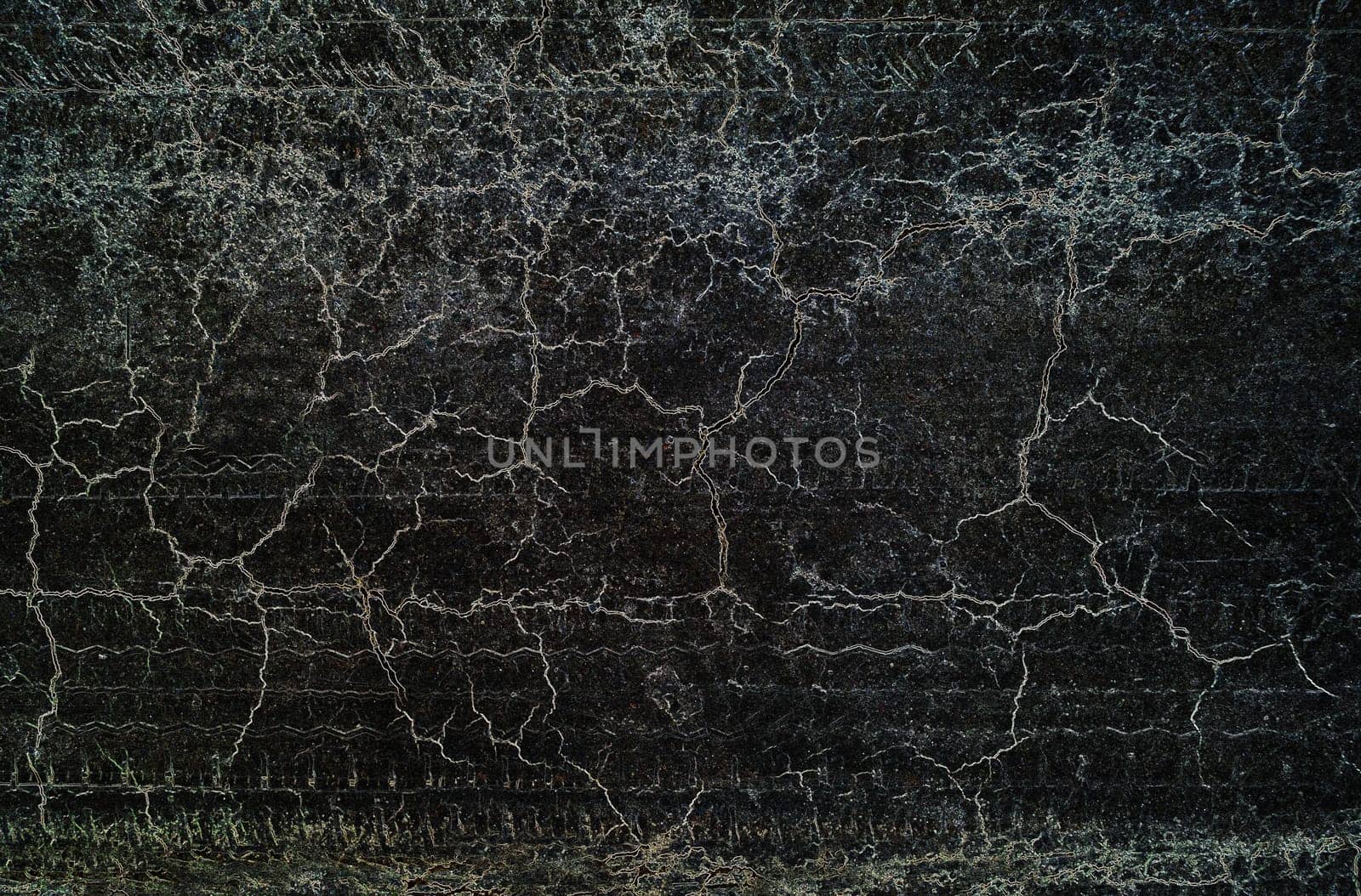 Grunge textured background with dirty surface and interlacing cracks on a black background