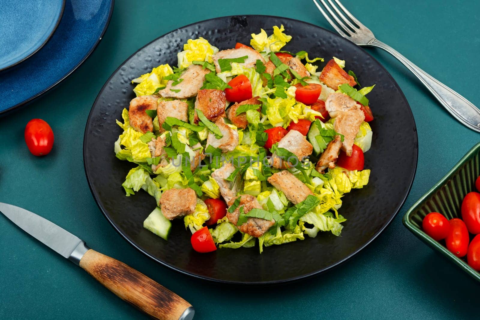 Salad with green lettuce, cucumber, tomatoes and pieces of meat. Top view.