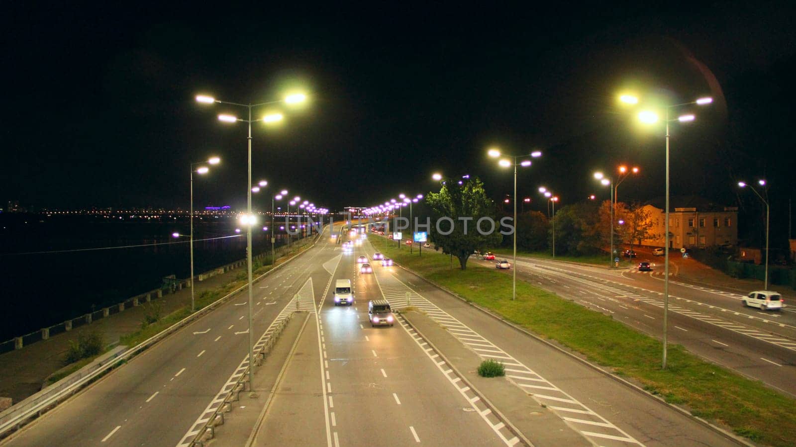 Evening transport. Cars on the night highway. Multi-lane road in Kyiv at night. Illuminated street of evening city. Cars going along night city