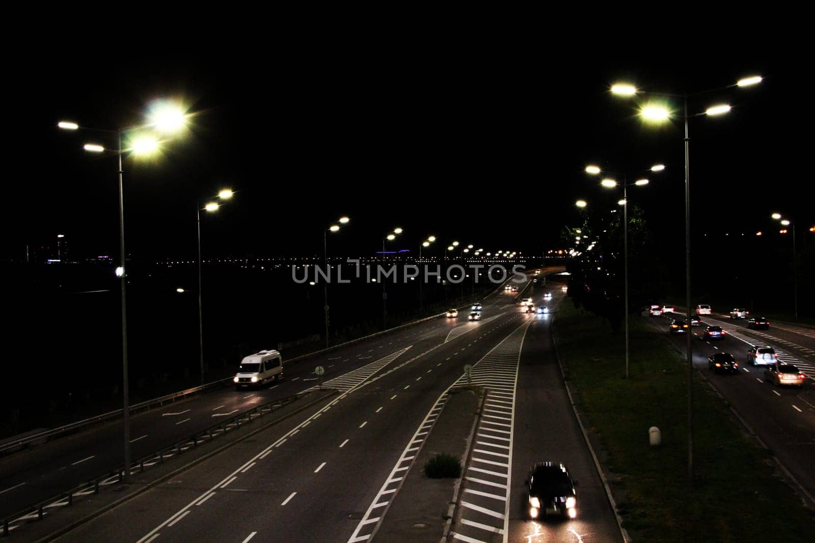 Evening transport. Cars on the night highway. Multi-lane road in Kyiv at night. Illuminated street of evening city. Cars going along night city