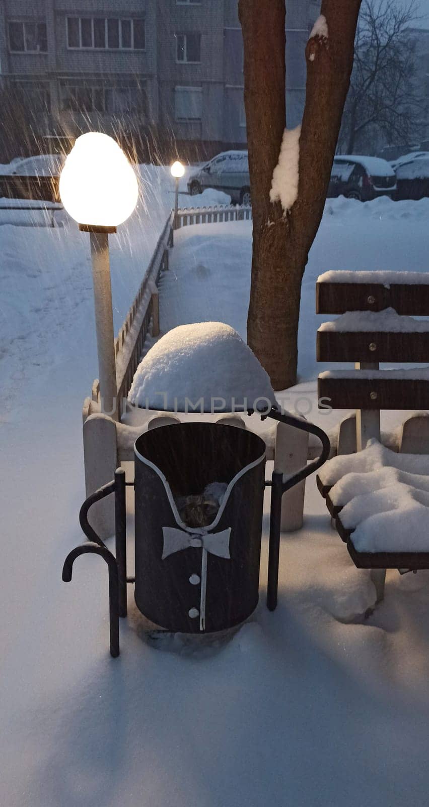 A figurative trash can in the form of a tailcoat and a hat in the snow in winter. Decorating a trash can near the entrance. Winter in the city. Snow cover on the trash can
