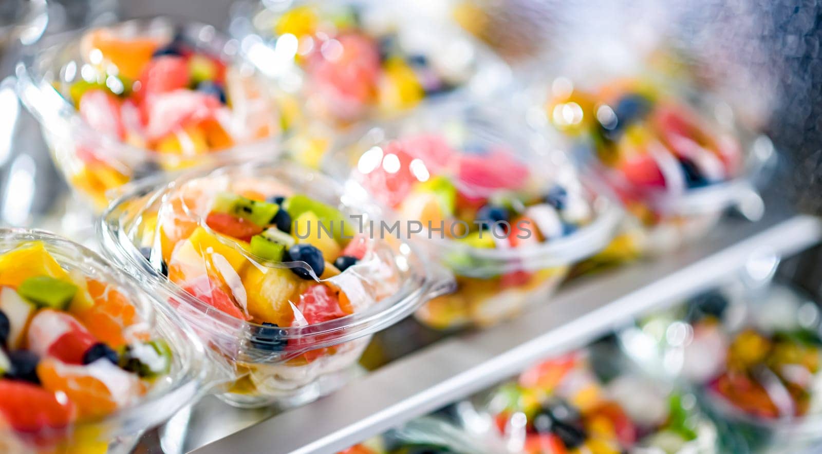 Plastic boxes with pre-packaged fruit salads, put up for sale in a commercial refrigerator