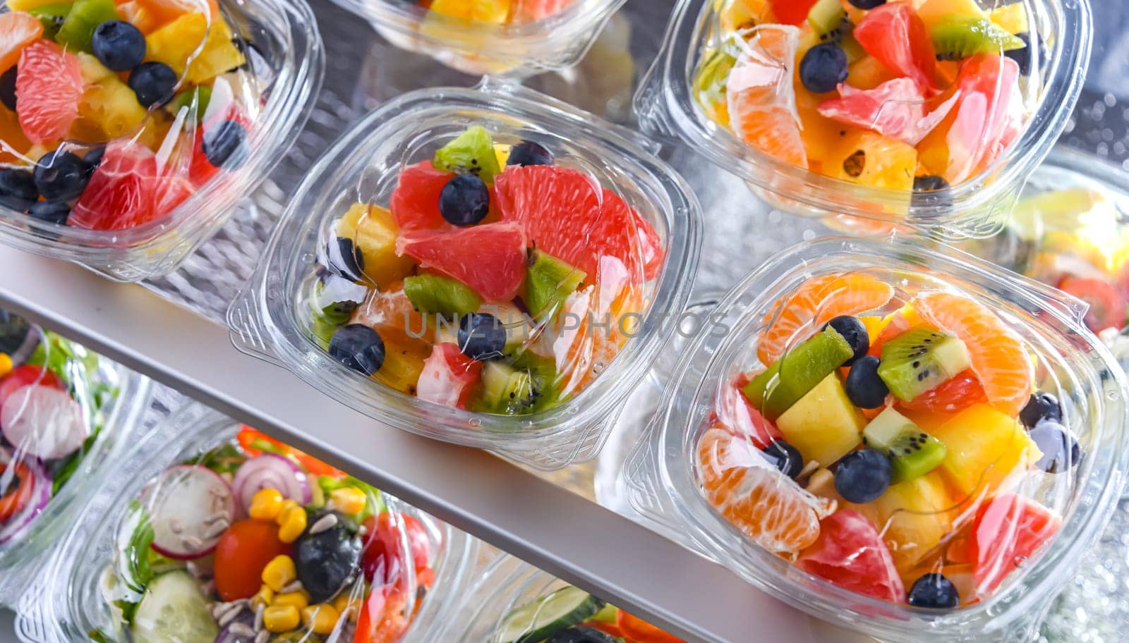 Plastic boxes with pre-packaged fruit salads, put up for sale in a commercial refrigerator