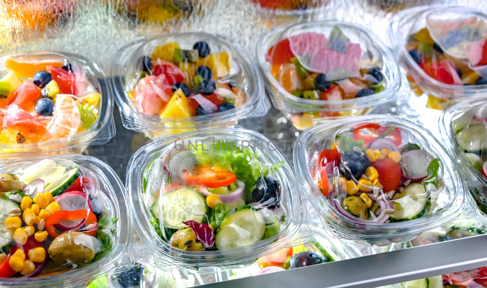 Plastic boxes with pre-packaged fruit and vegetable salads, put up for sale in a commercial refrigerator