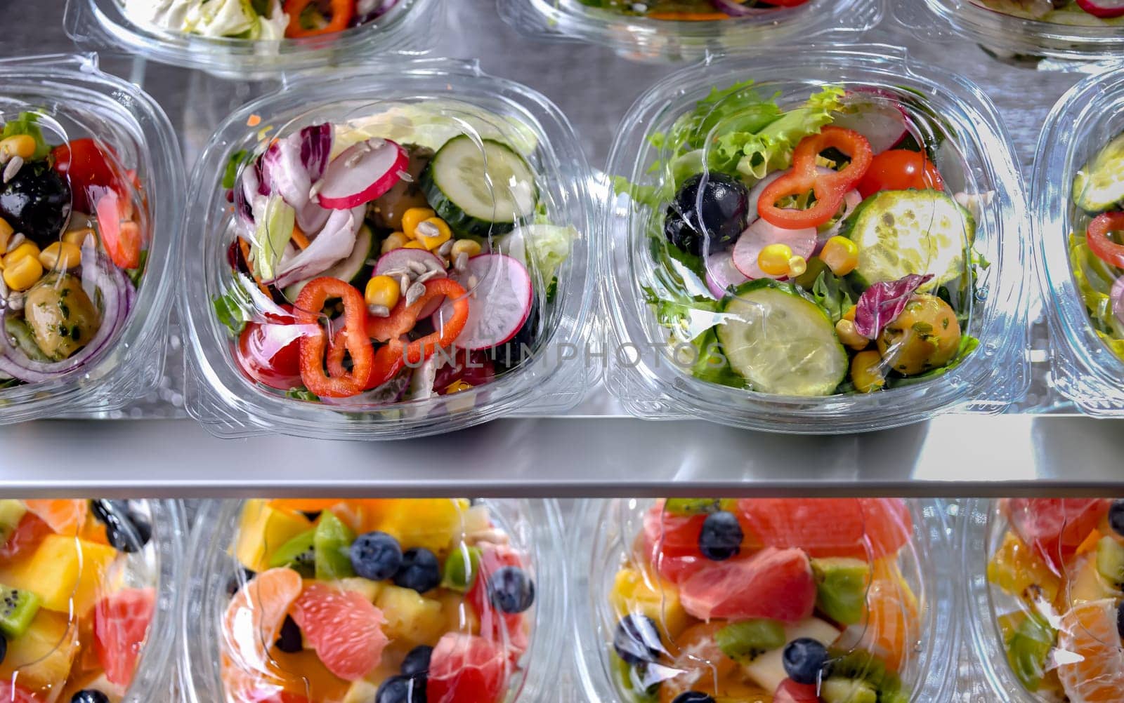 Plastic boxes with pre-packaged vegetable salads, put up for sale in a commercial refrigerator
