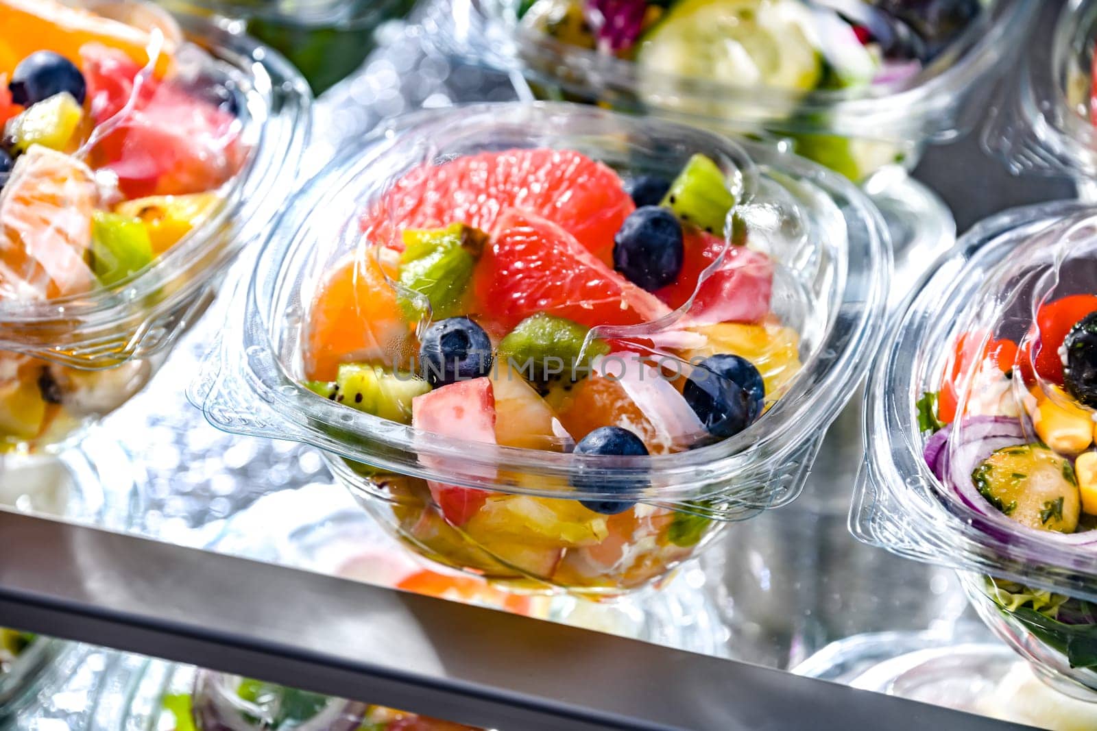 Plastic boxes with pre-packaged fruit salads, put up for sale in a commercial refrigerator