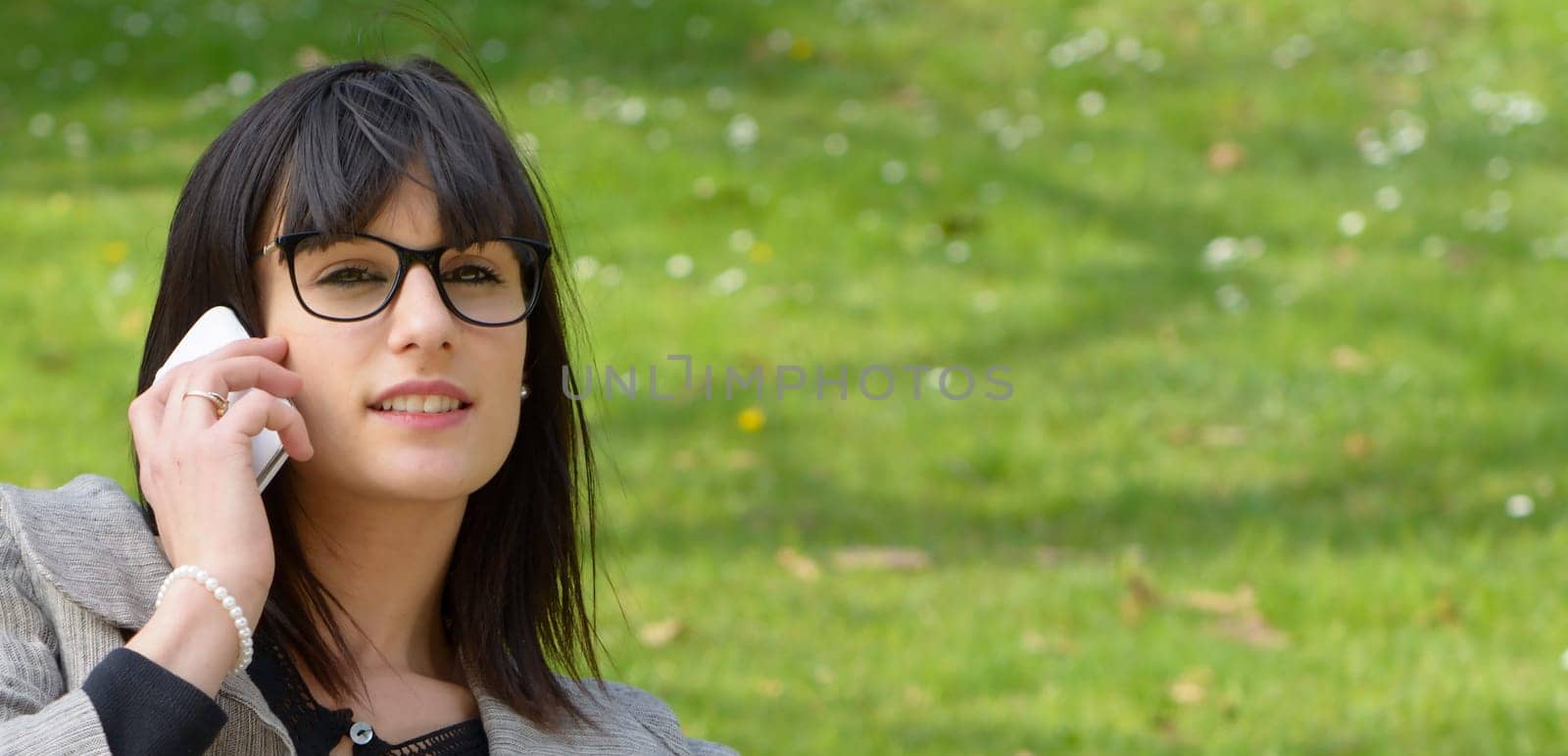 beautiful young brunette girl  with a mobile phone in park, outdoors