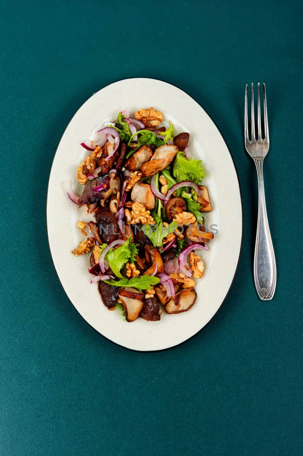 Autumn salad with stewed mushrooms, onions, lettuce and walnuts. Concept healthy food.