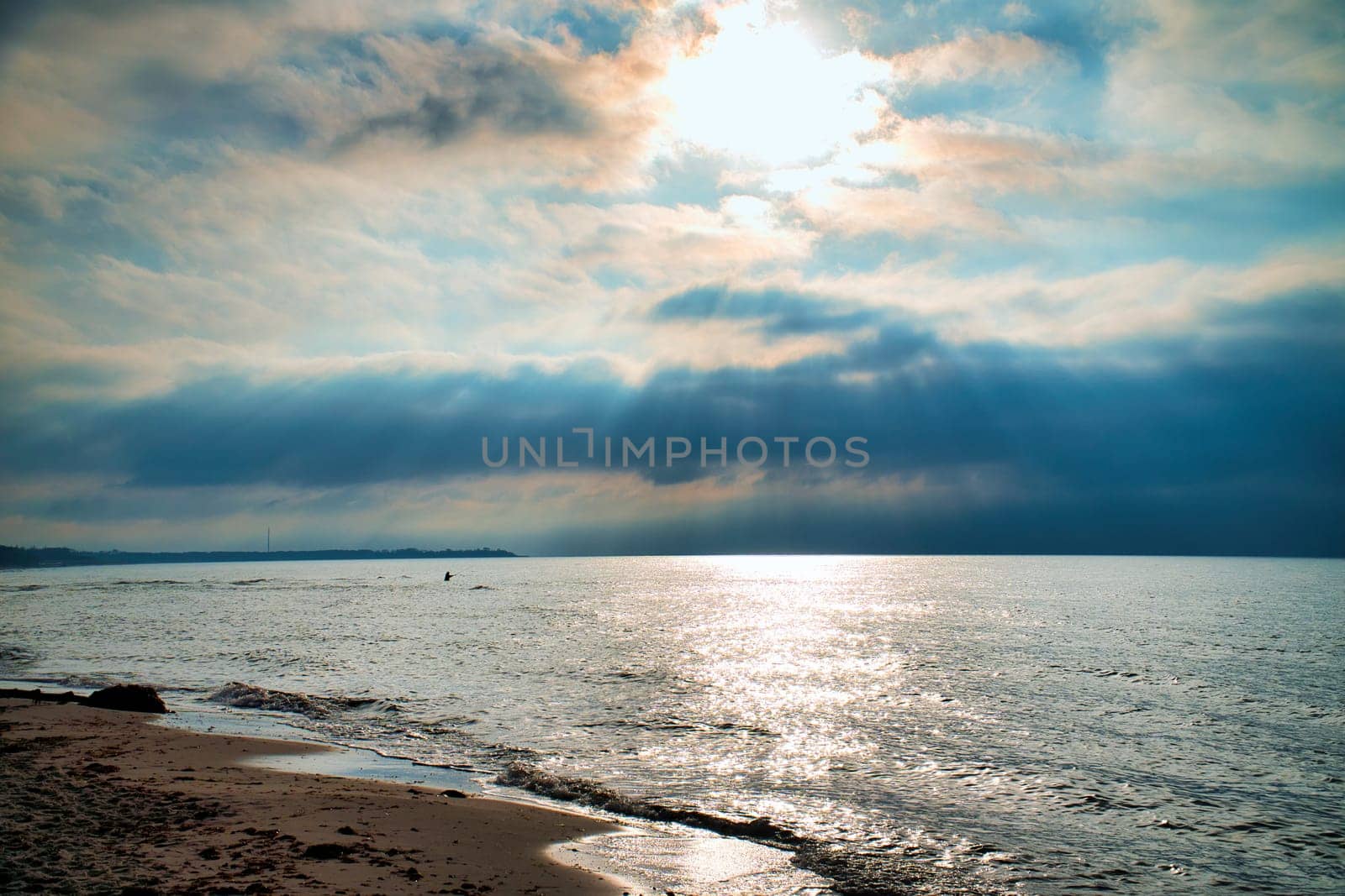Sunset, illuminated sea. Sandy beach in the foreground. Light waves. Baltic Sea. Landscape on the coast