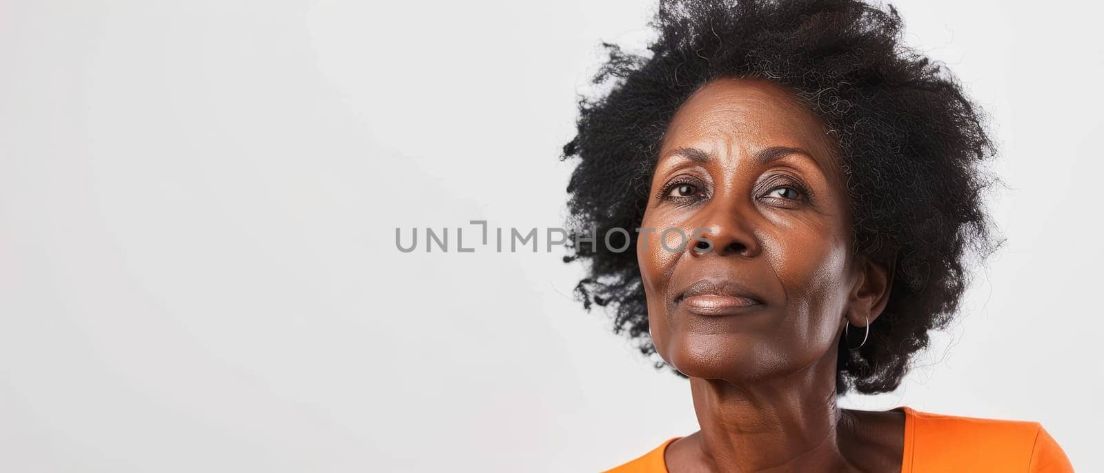A portrait of a senior African woman gazing upwards, her expression a blend of wisdom and introspection. The subtle orange attire contrasts with her dignified grey hair
