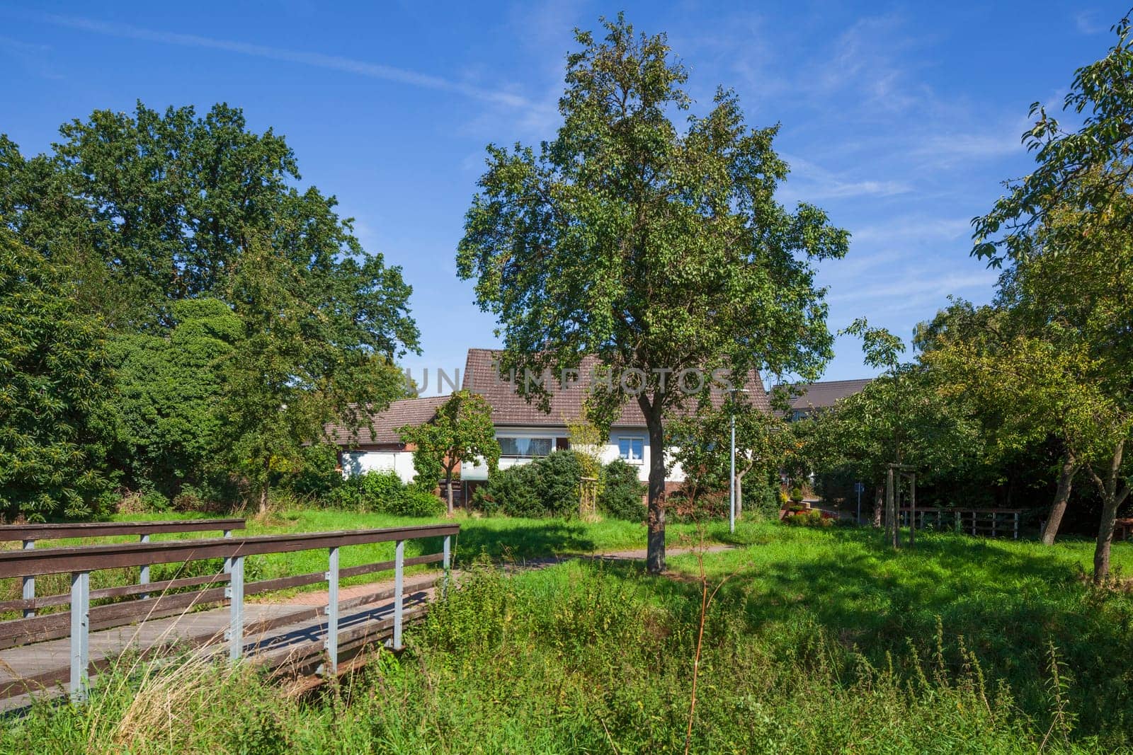 Pedestrian bridge with path in a green area and residential buildings, Wunstorf, Lower Saxony, Germany