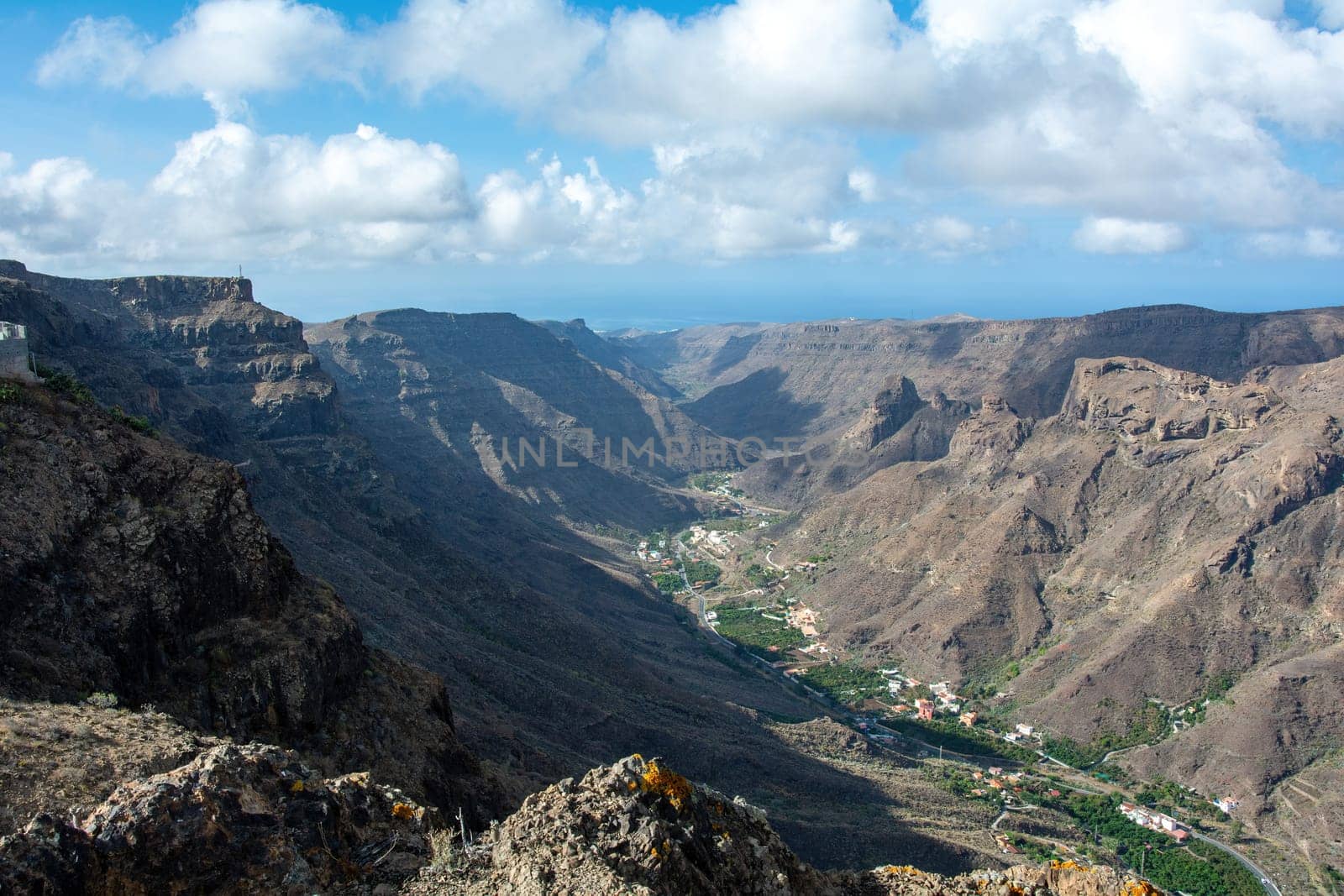 Mountains with a small village in the valley on the Canary Island of Gran Canaria in Spain, with blue sky and clouds