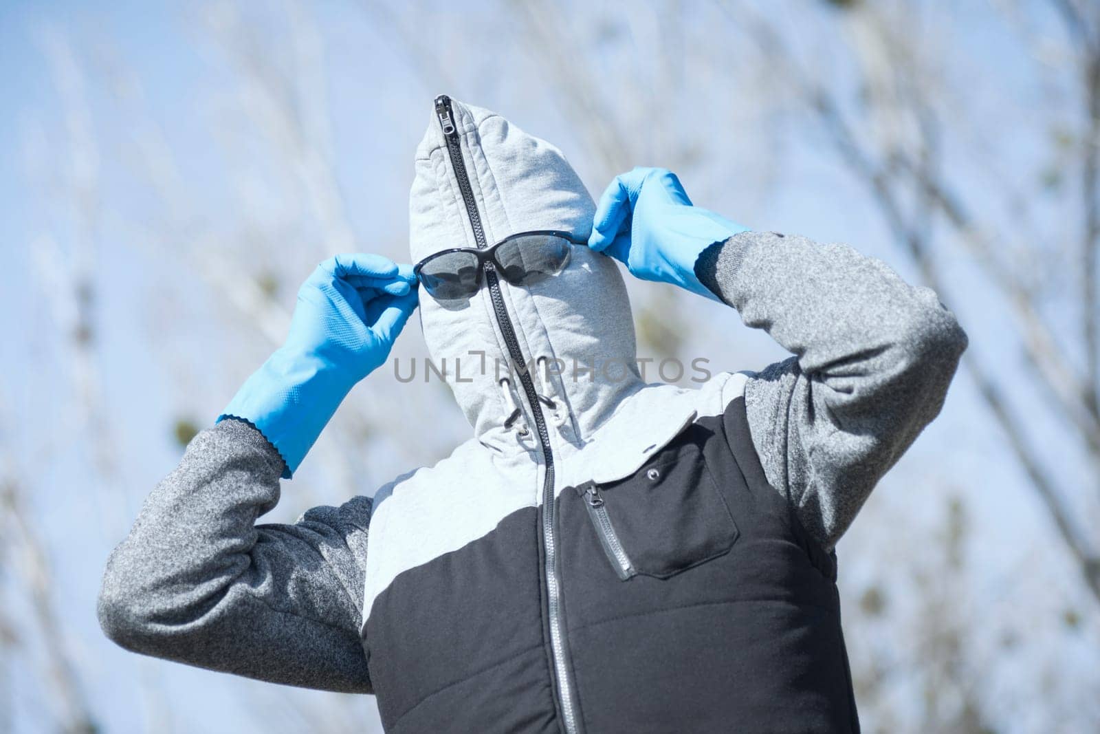 The funny man in vest with hood is wearing sunglasses, protective wear in coronavirus pandemic.