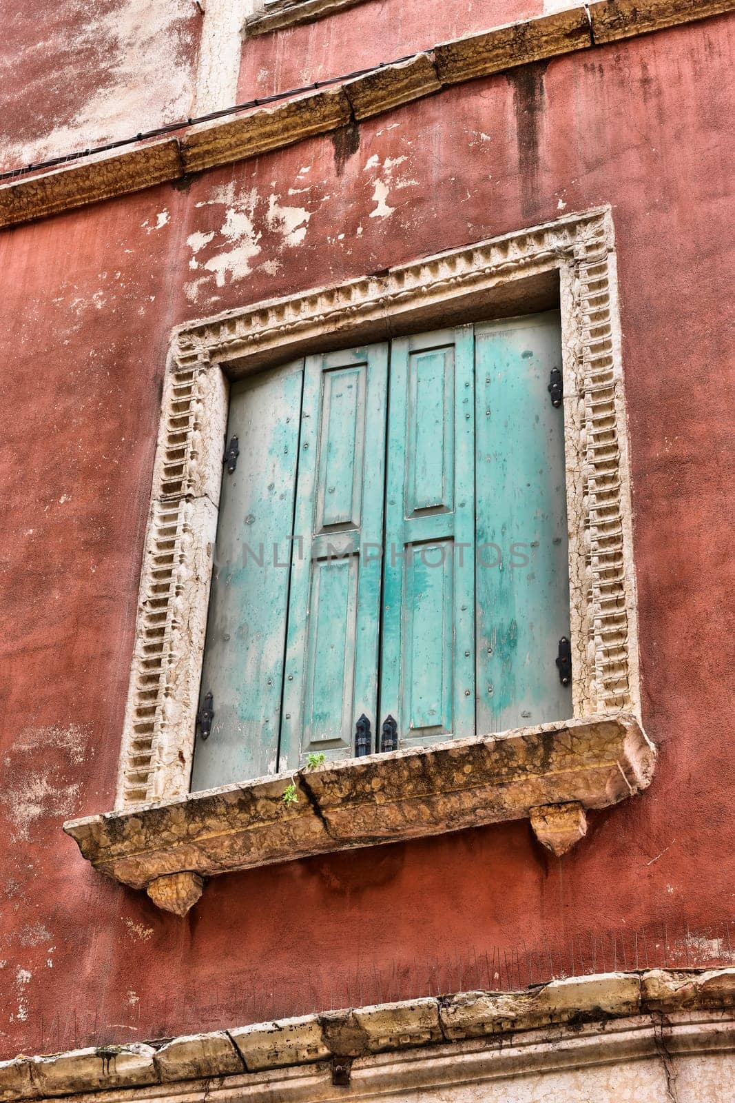 Window with green shutters on an old historic building in the old town of Verona in Italy