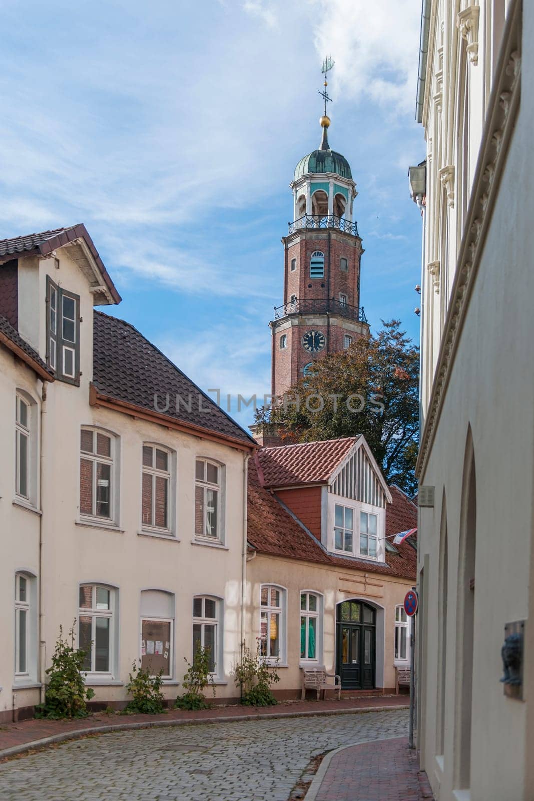 Bell tower of the large Reformed church in East Frisia in autumn 2022 in sunny weather with light veiled clouds.