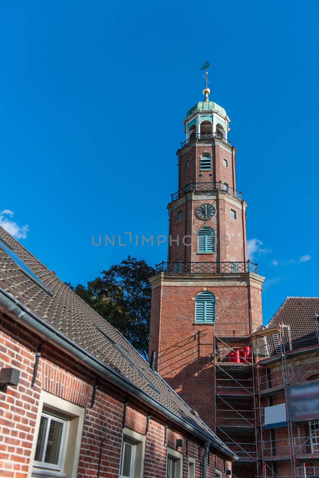 Bell tower of the large reformed church with scaffolding for maintenance work in East Frisia in autumn 2022 in sunny weather with blue sky.