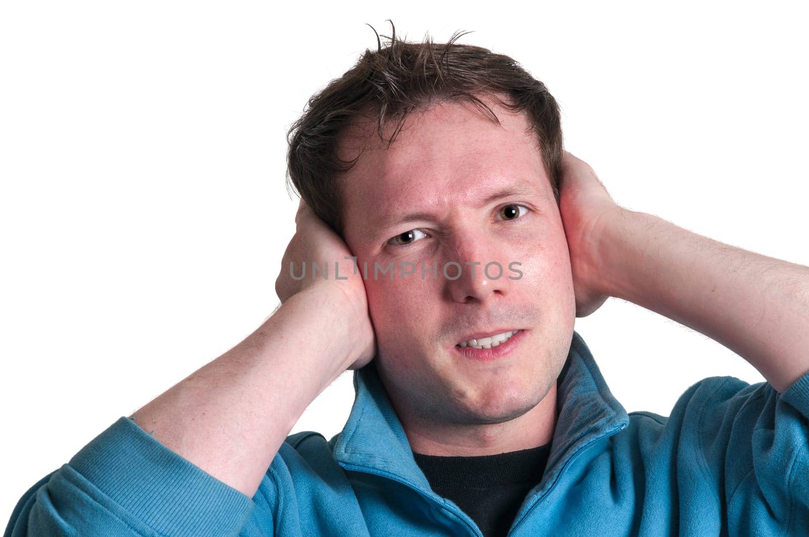 Frontal head portrait of a young brunette Caucasian man holding his hands to his ears with an angry expression and looking at the camera isolated on white.