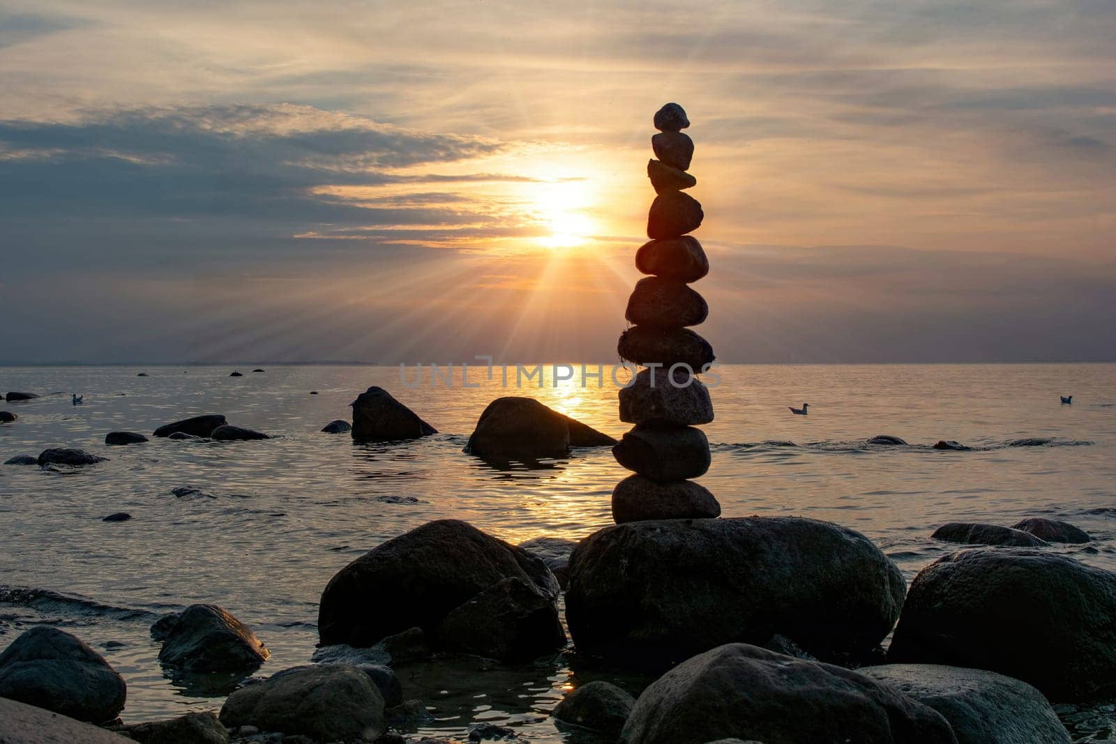 Stacked stones on a beach on the Baltic Sea coast at orange sunset