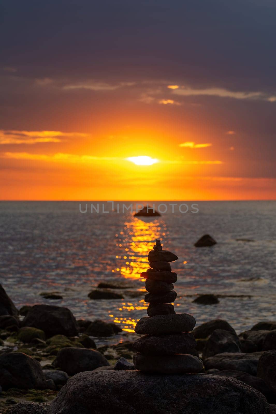 Stacked stones on a beach on the Baltic Sea coast at orange sunset