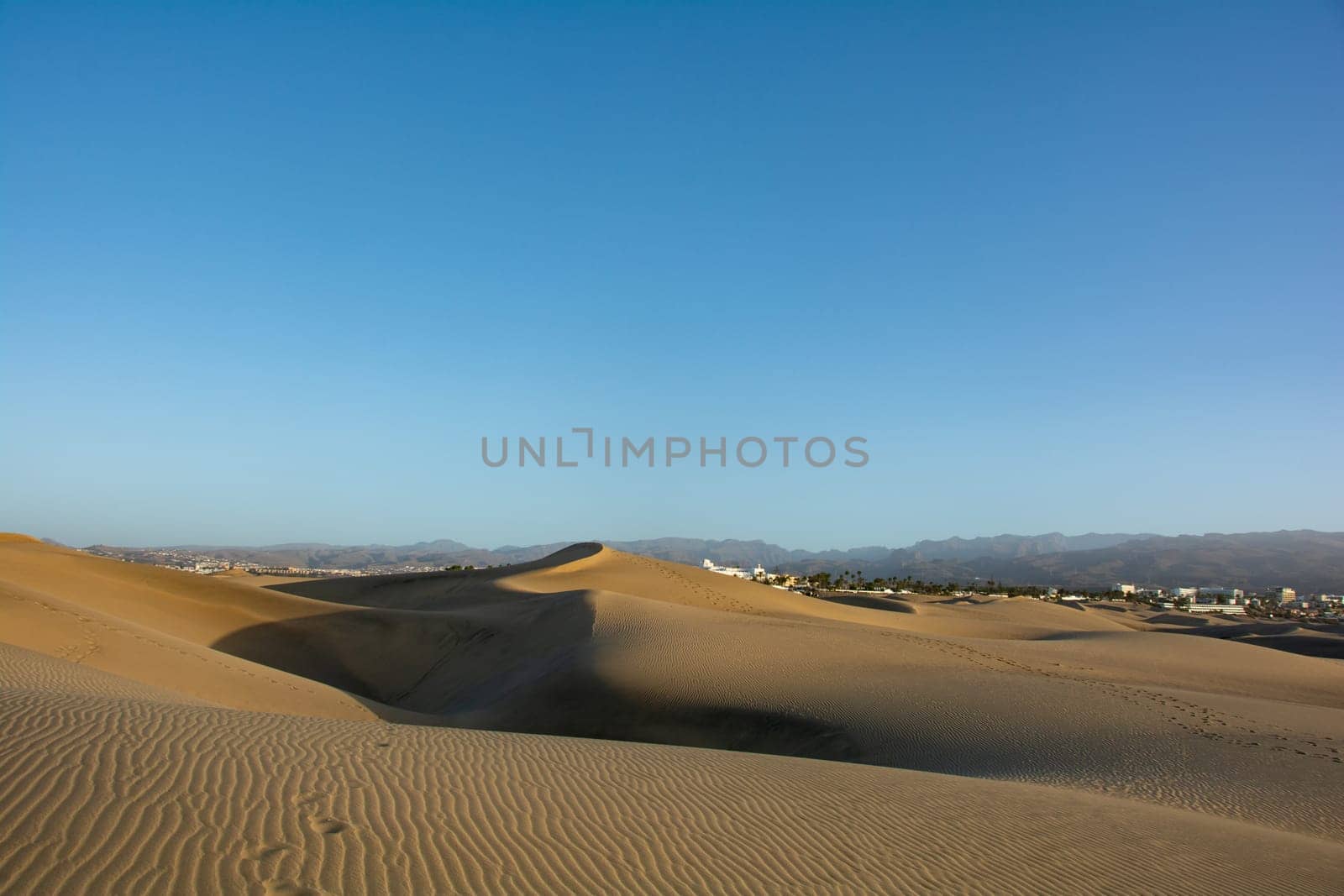 Sand dunes of Maspalomas with a view to the town of Playa del Inglés on the Canary Island of Gran Canaria, Spain, Europe. The huge sand dunes resemble a small desert and are a nature reserve.