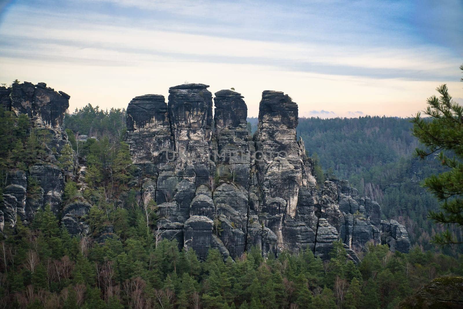 Rugged rocks on the Basteibridge. Wide view over trees and mountains. National park in Germany