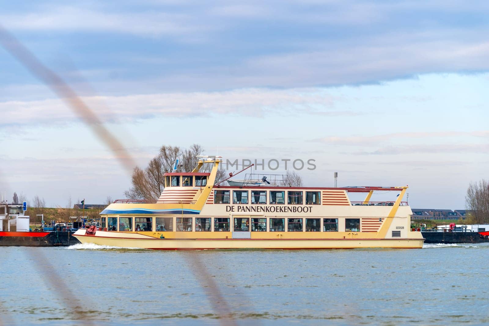 NIJMEGEN, NETHERLANDS - MARCH 9, 2024: Touristic boat called "De Pannenkoekenboot"" (the pancake boat) on the Waal River in the Netherlands."